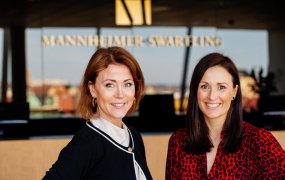 Karin Mendel och Johanna Ärlund står med Mannheimer Swartling-loggan bakom sig. 