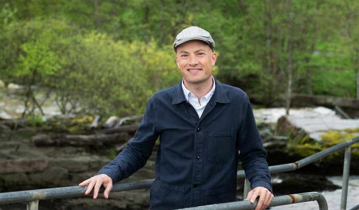 Andreas Severinsson står på en bro med grönska bakom sig. 