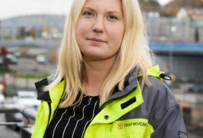 Jenny Karlsson står utomhus med en byggarbetsplats i bakgrunden.