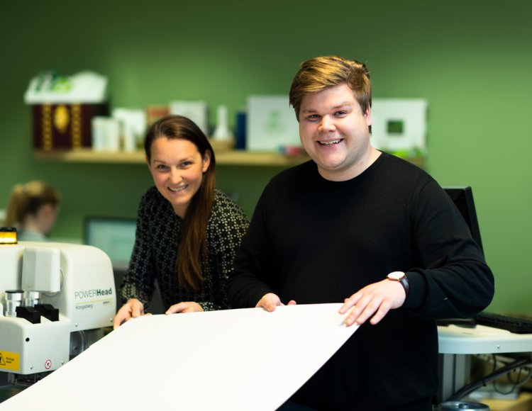 Carl Johansson visar en skogsindustribolagets produkter i form av ett stort vitt ark tillsammans med en kollega. 