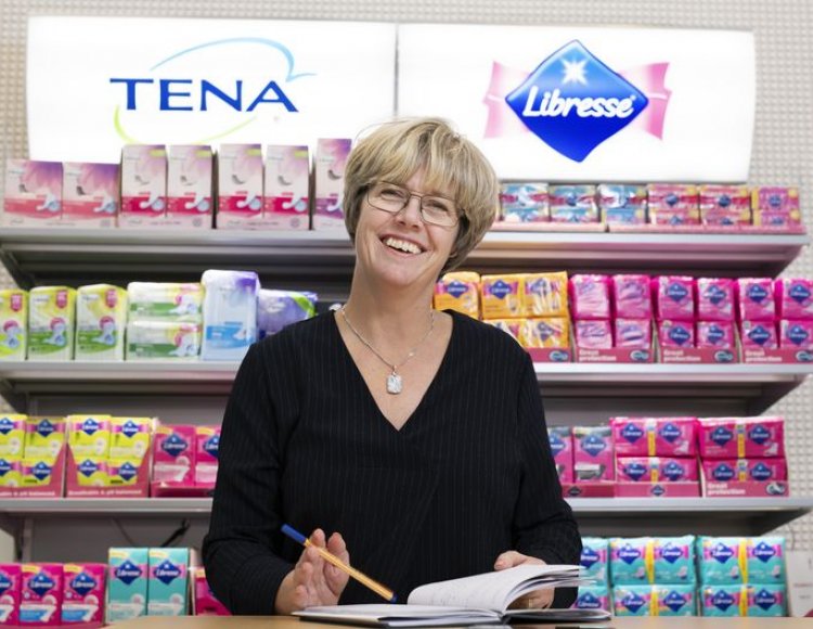 Anna-carin Elfström ståendes framför en hylla full av essitys färgglada produkter som Tena och Libress.
